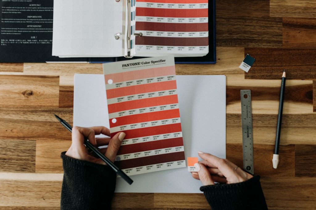 a person holding a pen over a paper with a color chart on it